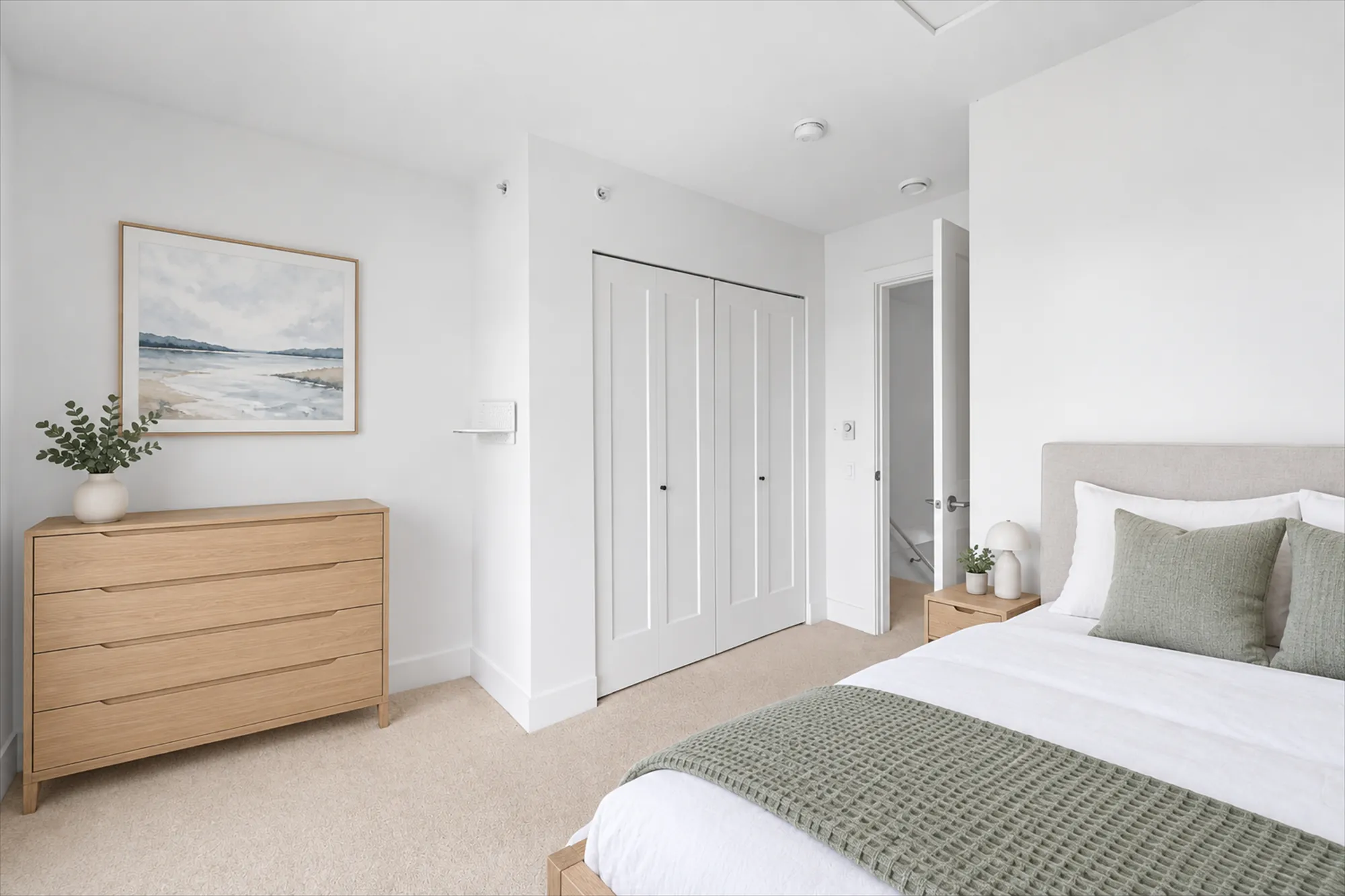 The back bedroom virtually staged, toward its double closet and the door to the hall: a bed with white linen, a wood dresser with a plant, a seascape picture