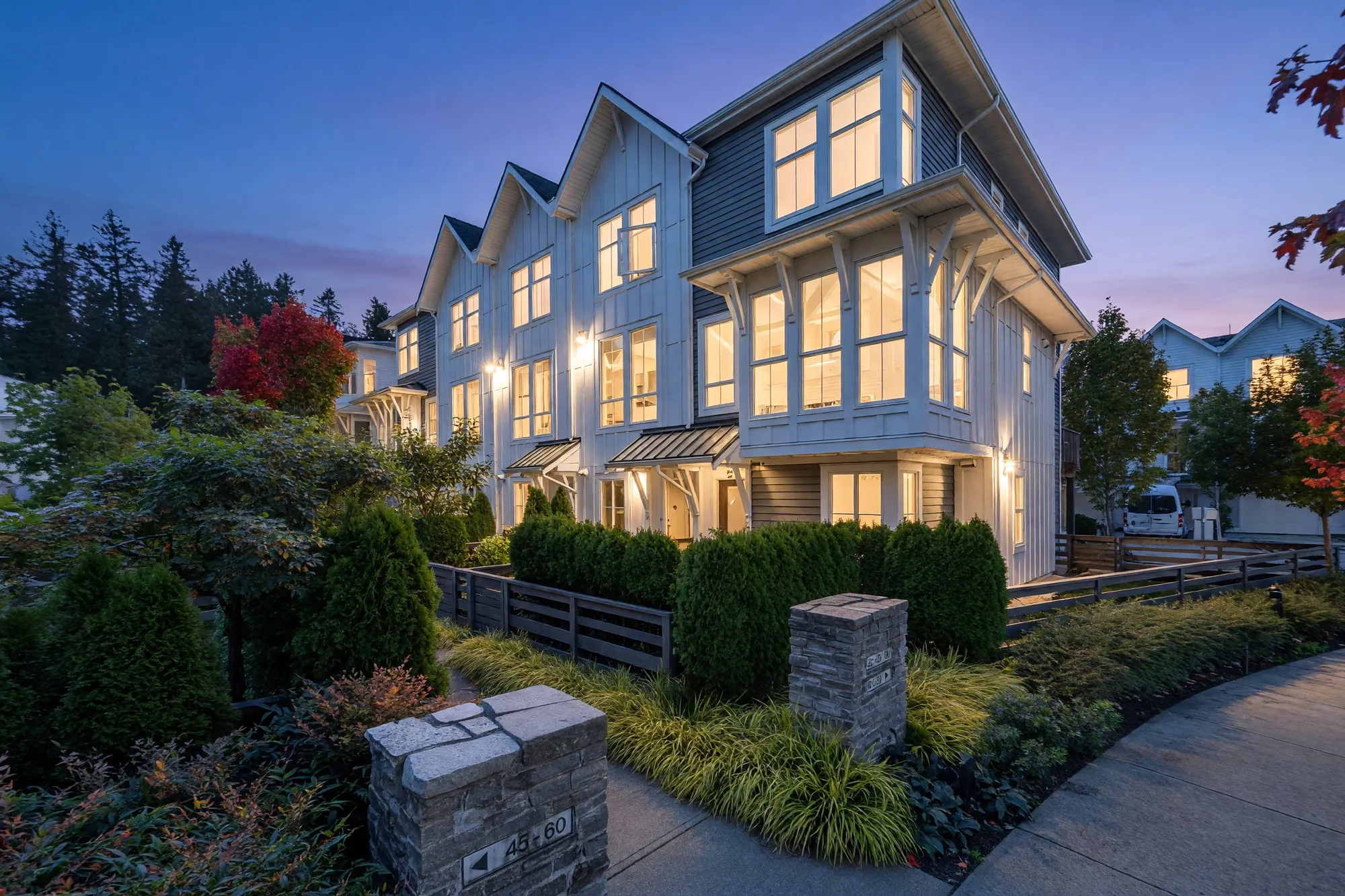The same corner at dusk, the windows and porch lights lit