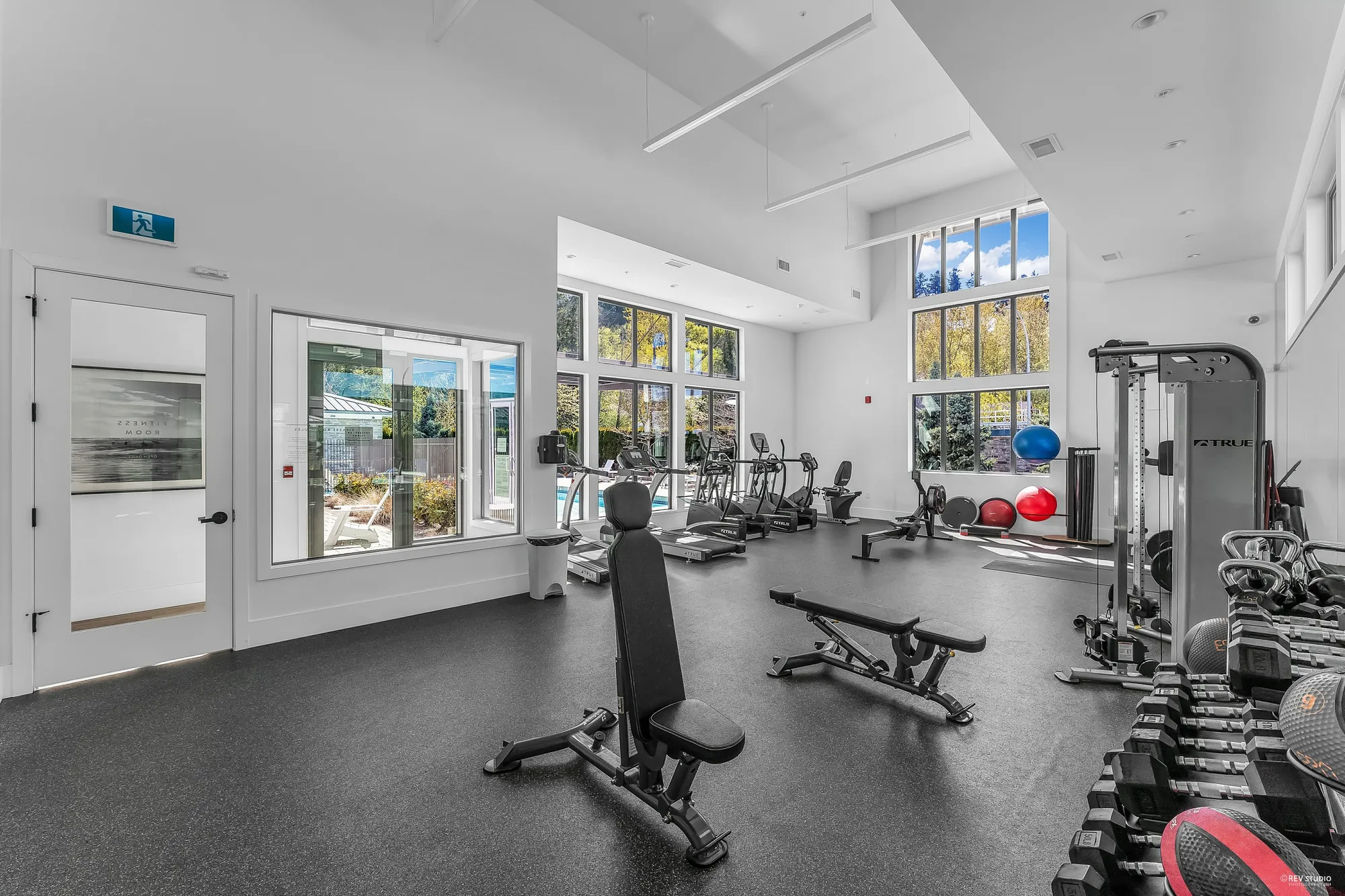 The exercise room: weights, benches and machines under tall windows