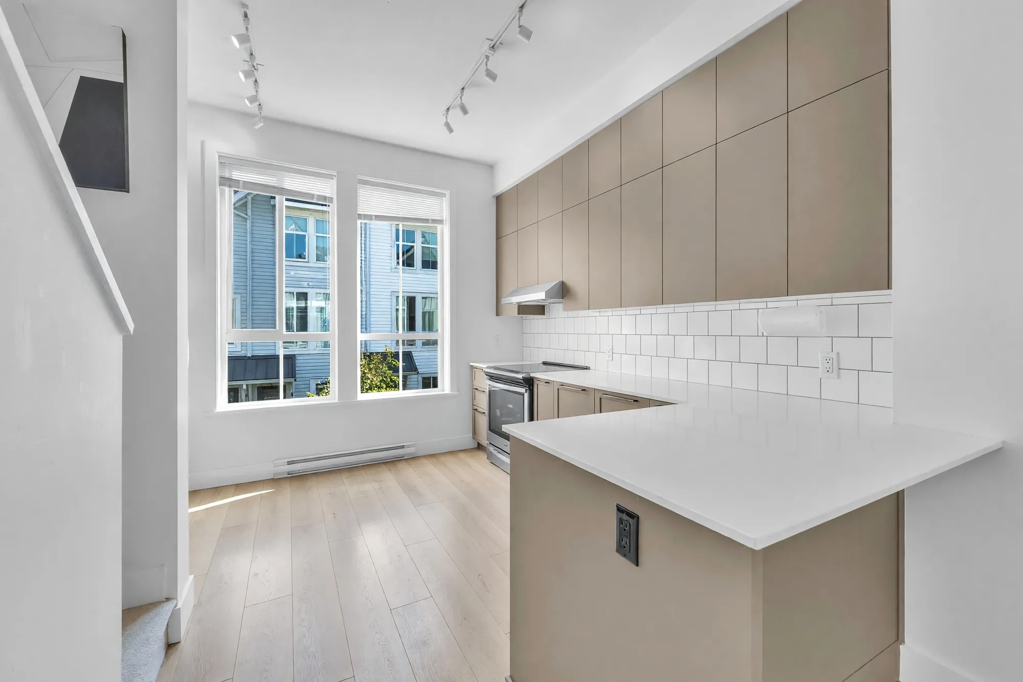 The peninsula and the front windows, shown cleared: white counters, grey cabinets, two windows onto the row across the walk