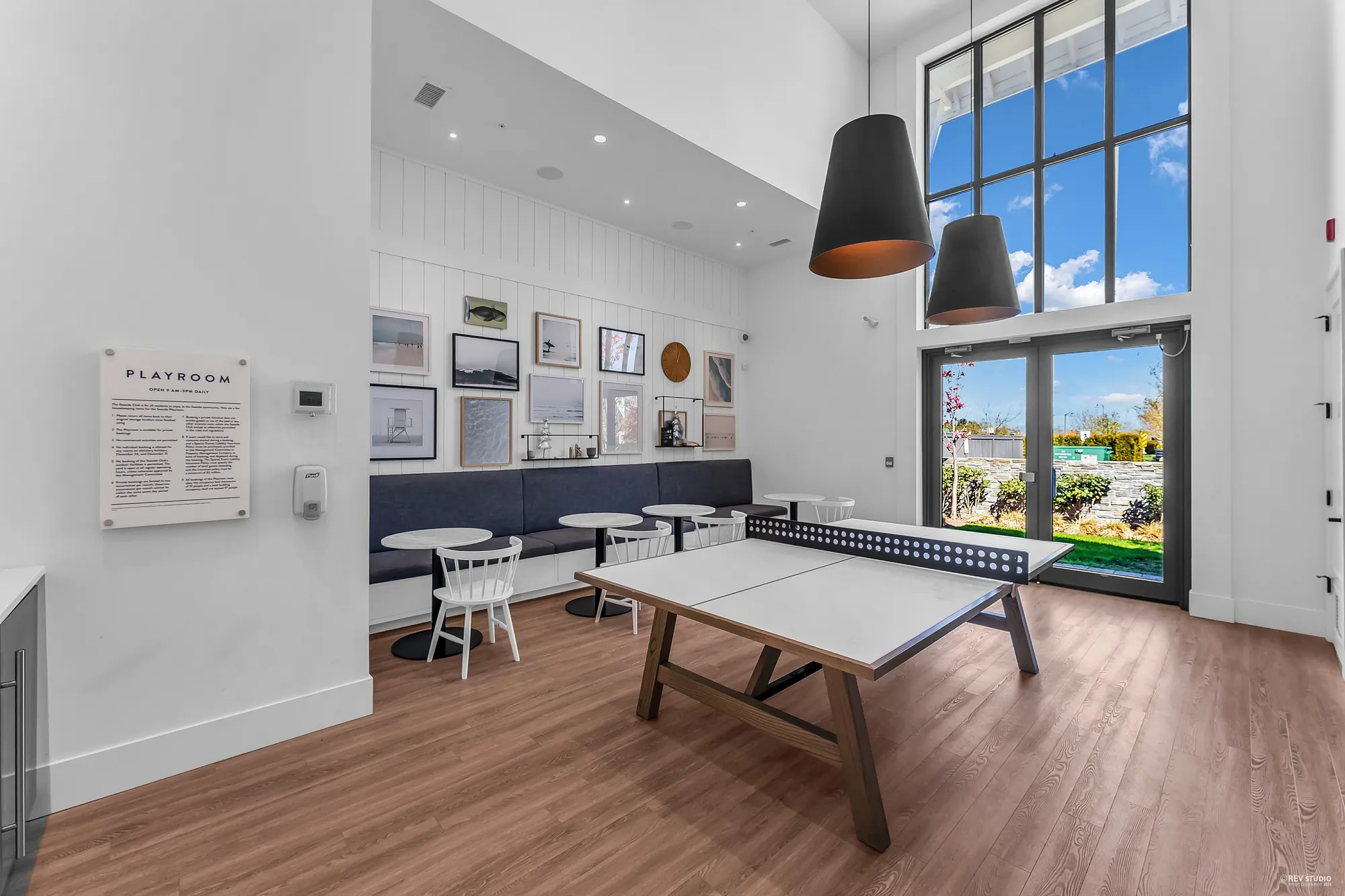 The playroom: a table-tennis table on a wood floor, a bench with small tables, tall windows
