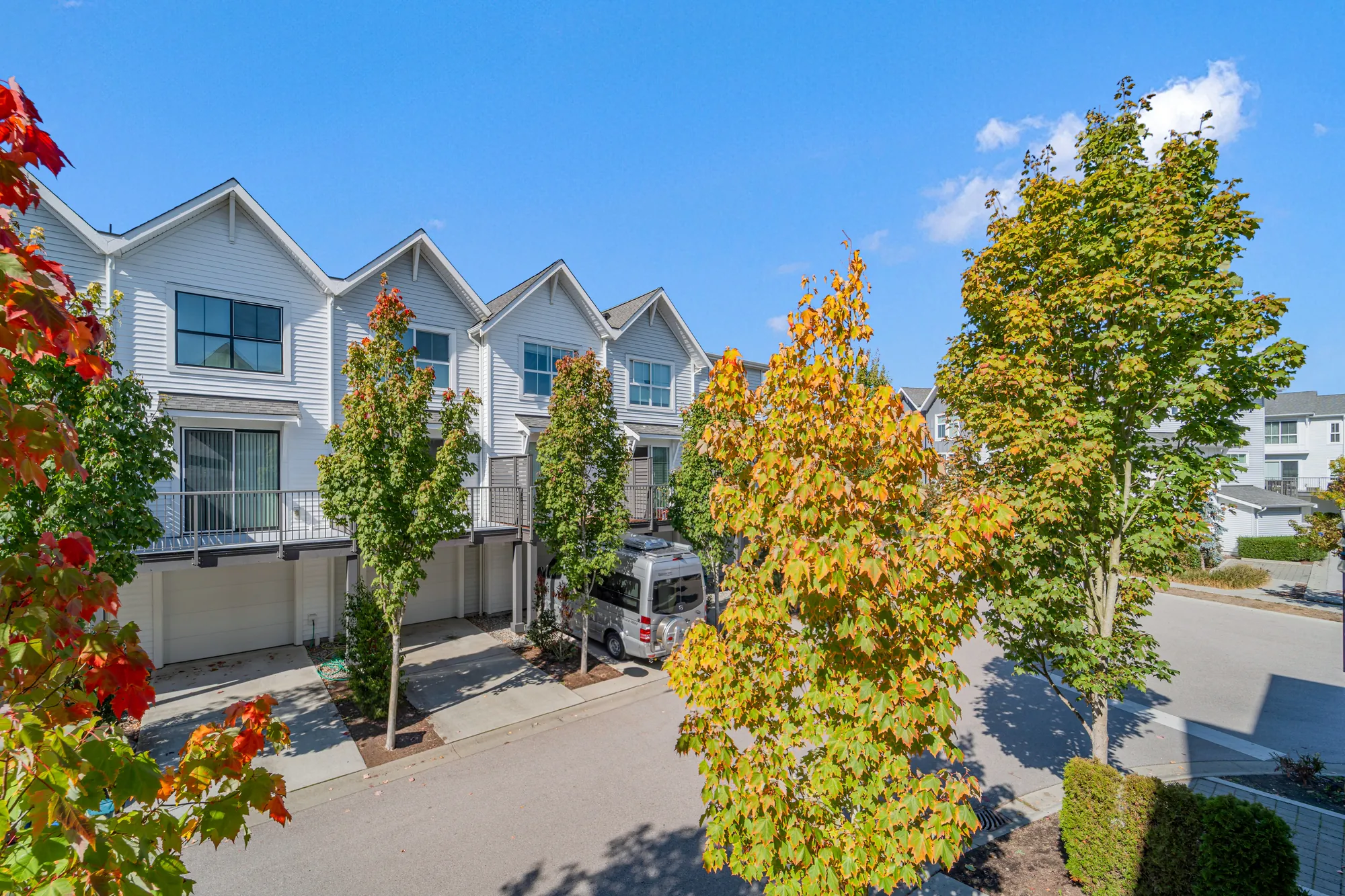From the balcony: the lane below, the row opposite with its balconies and garages, maples in autumn colour